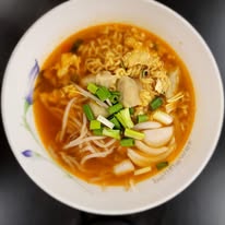 A bowl of spicy noodle soup with green onions